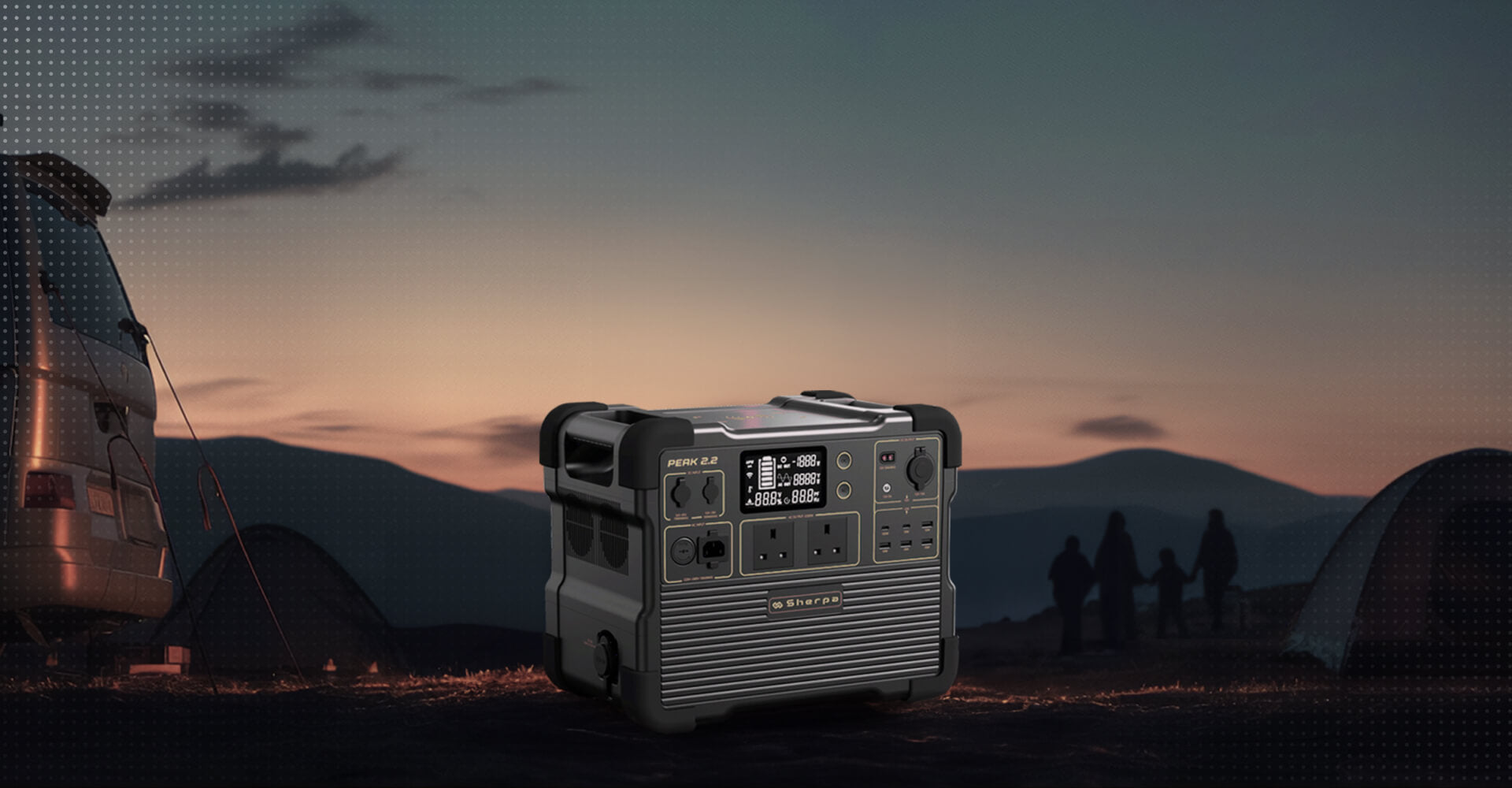 A portable battery inverter unit sits on a grassy surface with a backdrop of a sunset camping scene and leisure van